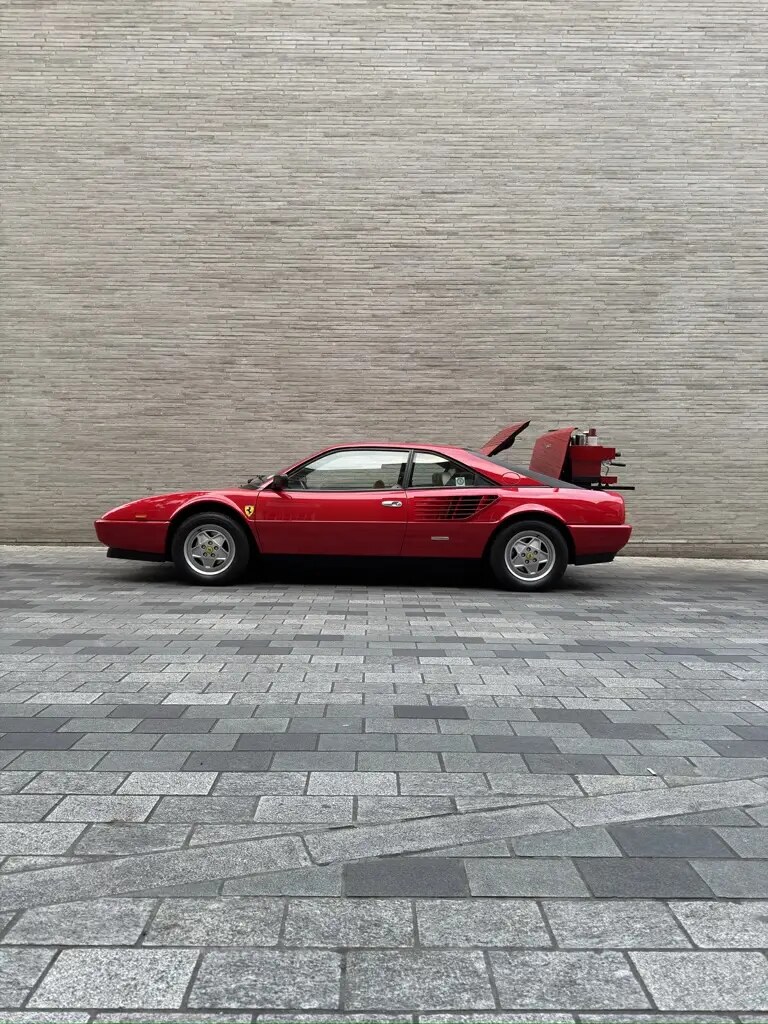Side profile of the red 1986 Ferrari Mondial with its espresso station open